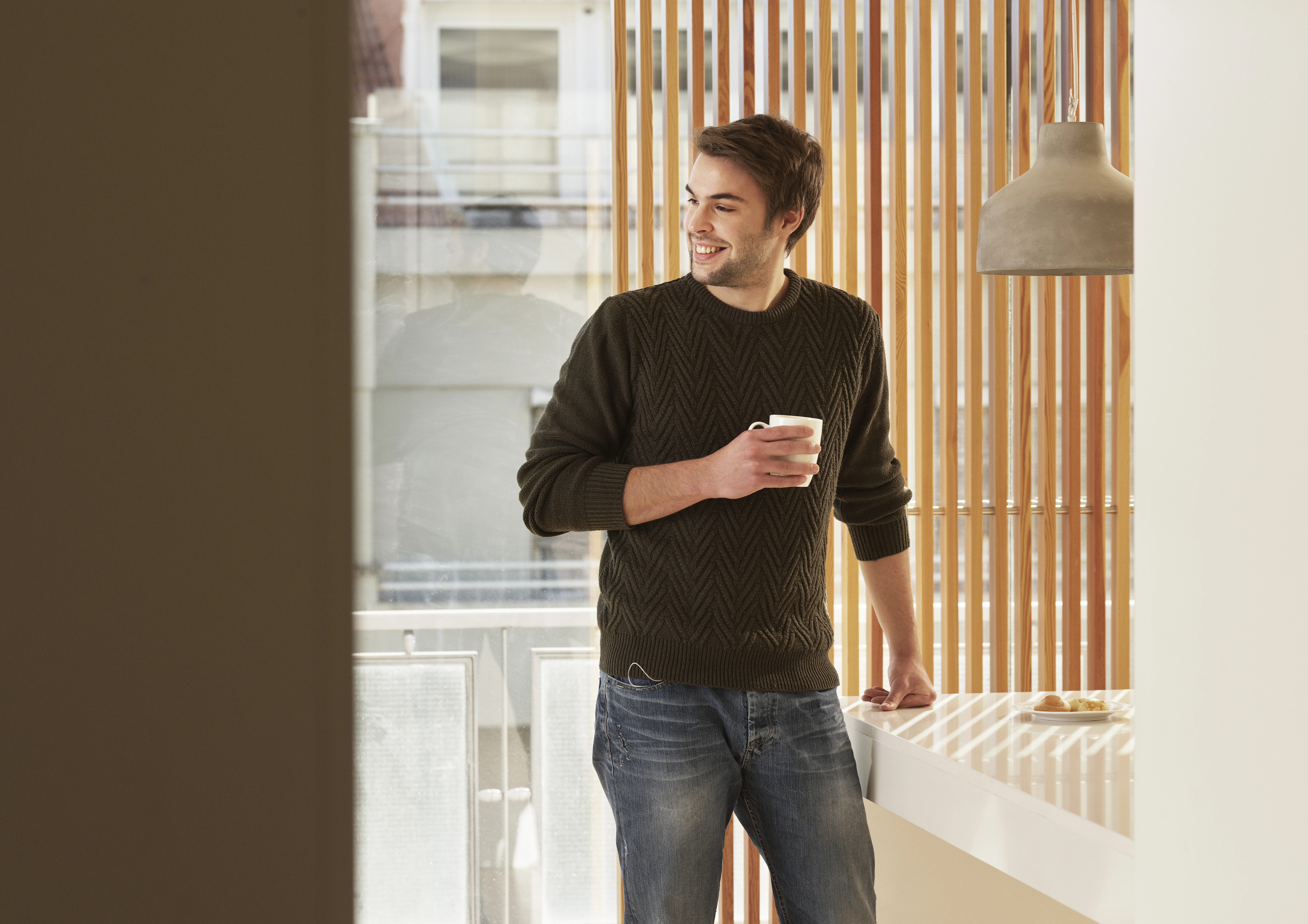 Ein Mann steht vor einem Fenster und hält eine Tasse