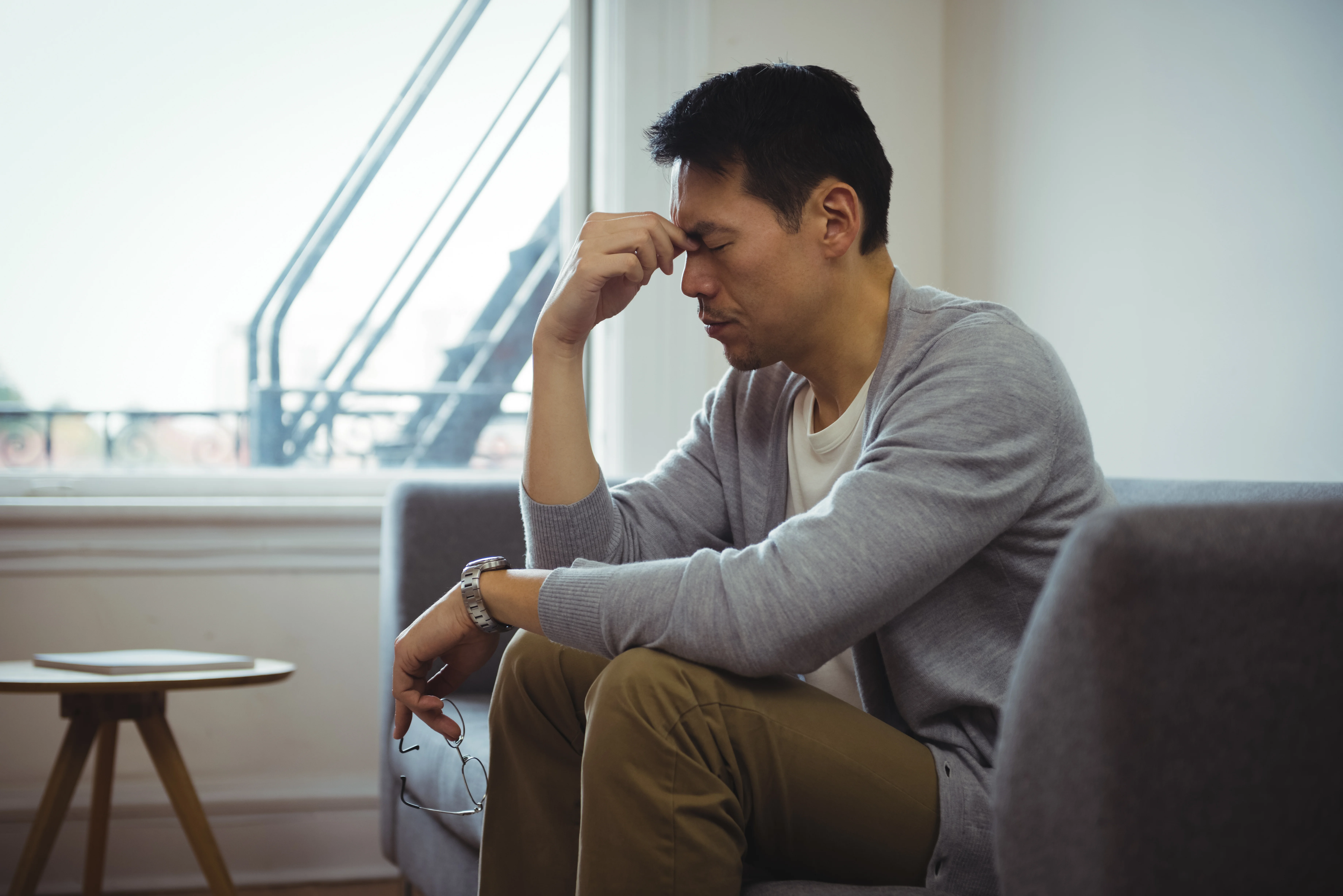 A man sitting on a couch looking defeated.